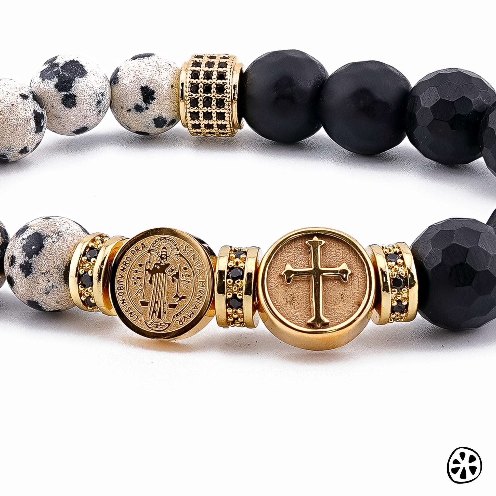Handmade St. Benedict & Cross Protection Bracelet featuring 9–10mm Dalmatian Jasper and faceted black onyx matte beads. Adorned with 18K PVD gold-plated double-sided saint charms and gold CZ brass spacers. A unisex bracelet symbolizing strength, protection, and faith, handcrafted in the USA. / Pulsera artesanal de San Benito y Cruz de protección con jaspe dálmata y ónix negro mate, hecha a mano en EE. UU., símbolo de fe, fuerza y protección.