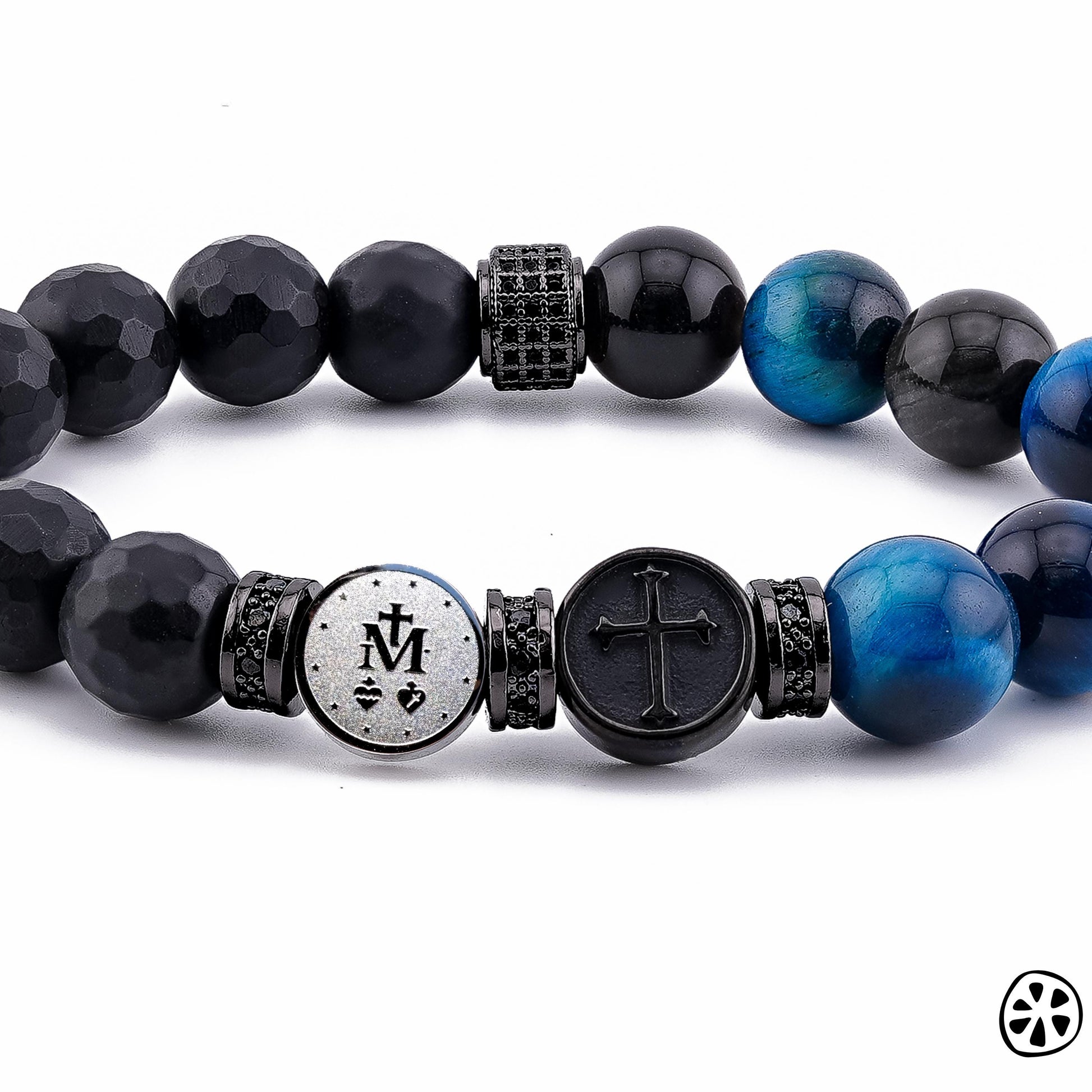 Close-up product image of a Miraculous Medal triple protection bracelet showing the double-sided stainless steel Marian symbol charm beside a black cross charm. The bracelet features faceted black onyx beads, glossy blue tiger eye gemstones, black-gray obsidian beads, and black CZ-accented spacers. Photographed on a clean white background with detailed focus on the textures and finishes.