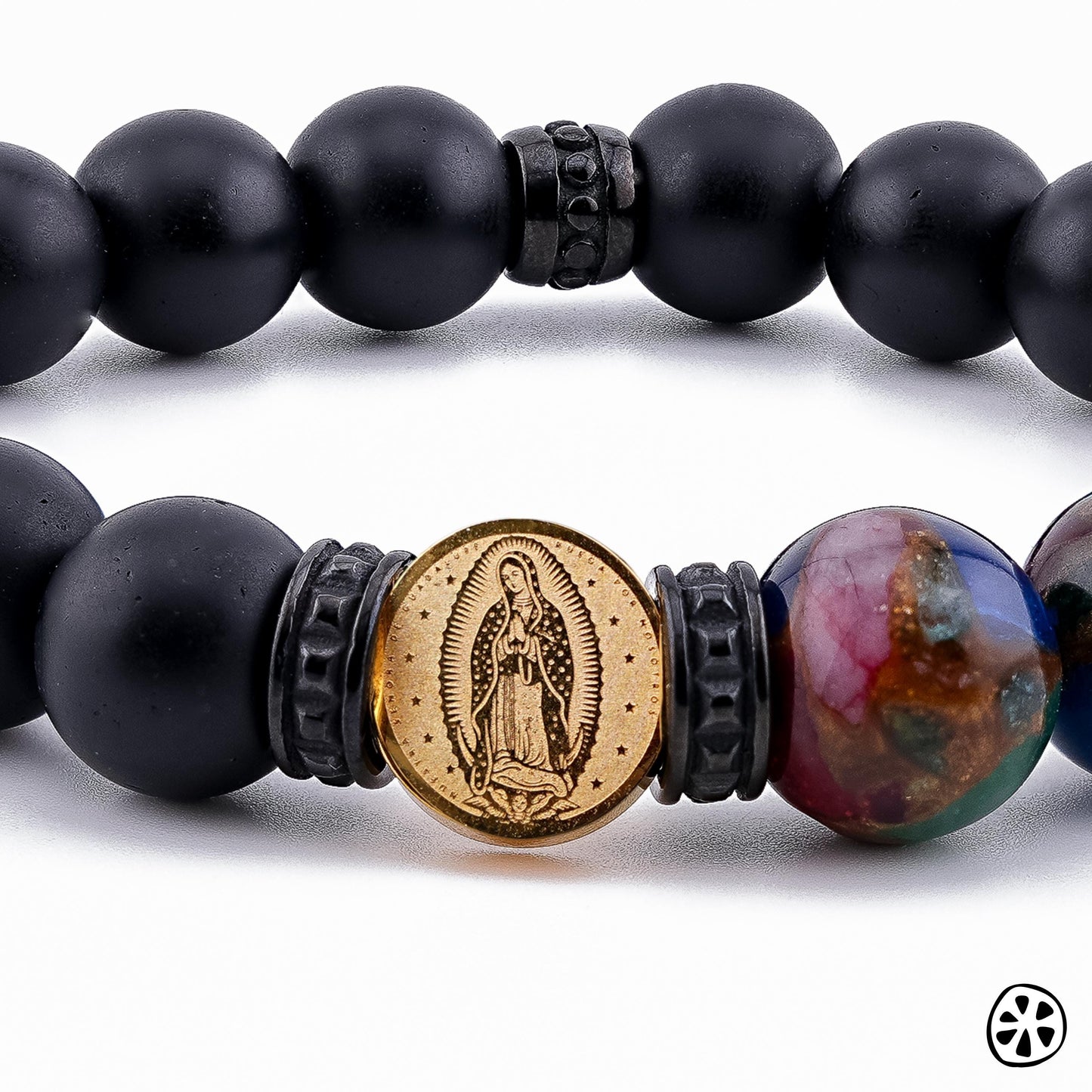 Close-up of Our Lady of Guadalupe bracelet showing gold-tone Guadalupe medal centered between black PVD stainless steel spacers, with 10mm frosted black onyx beads and multicolor cloisonné accent bead. Handmade Catholic jewelry for men and unisex wear, highlighting fine details and durable materials. Faith-inspired bracelet ideal for prayer, everyday wear, or gifting for confirmation, baptism, or religious occasions.