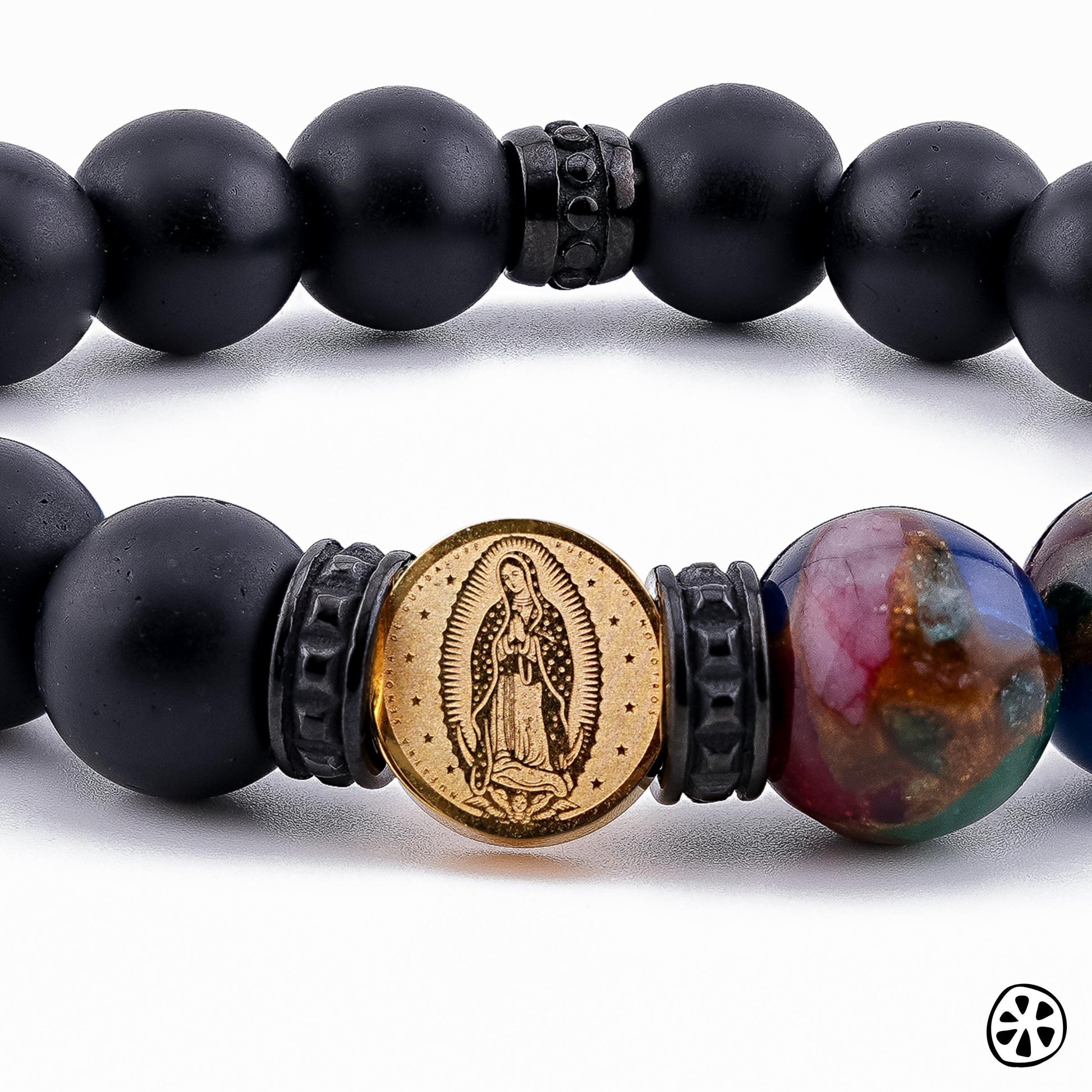 Close-up of Our Lady of Guadalupe bracelet showing gold-tone Guadalupe medal centered between black PVD stainless steel spacers, with 10mm frosted black onyx beads and multicolor cloisonné accent bead. Handmade Catholic jewelry for men and unisex wear, highlighting fine details and durable materials. Faith-inspired bracelet ideal for prayer, everyday wear, or gifting for confirmation, baptism, or religious occasions.