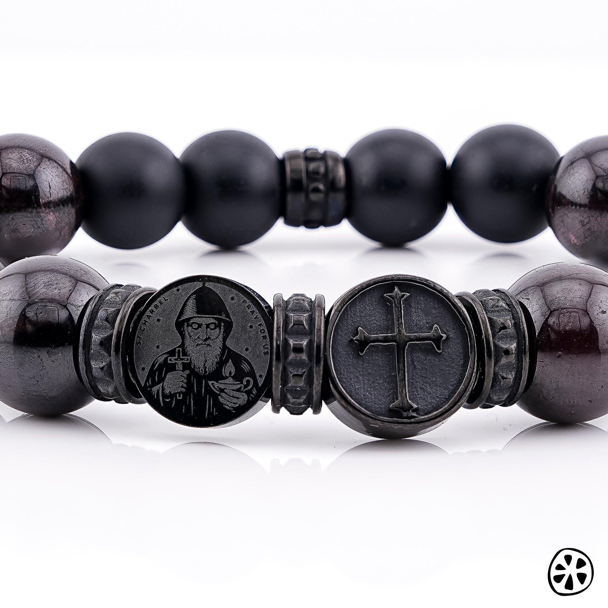 Men’s St. Charbel and cross bracelet close-up, matte black onyx and polished garnet gemstone beads 10mm, Catholic men’s jewelry, black PVD stainless steel St. Charbel medal with cross charm detail, handmade in USA, faith bracelet for men, protection bracelet, rosary chaplet style, Christian jewelry, masculine stretch bracelet, spiritual gift for him, premium gemstone bracelet, religious bracelet men unisex, gift for dad husband boyfriend