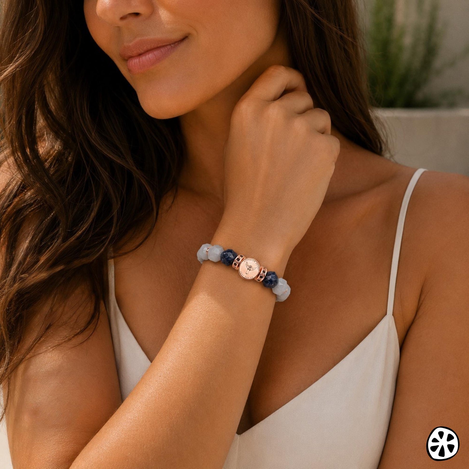 Elegant woman wearing a St. Michael and Guardian Angel bracelet with faceted aquamarine and blue sodalite gemstones, rose gold PVD plated stainless steel saint medal charm, and rose gold CZ brass crystal spacers. Feminine Catholic inspired jewelry traditionally associated with peace, wisdom, emotional balance, guidance, courage, and protection. Modern faith bracelet for everyday wear, meaningful gifting, nurses, caregivers, mothers, teachers, healthcare workers, and loved ones.